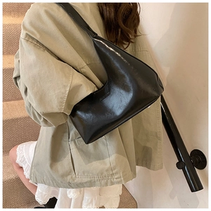 Close-up of a glossy black crescent hobo bag with subtle logo and premium leather texture
