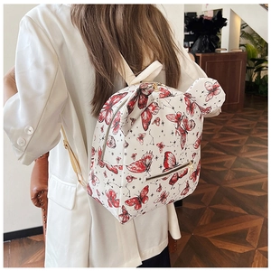 Detail showing white PU backpack with red butterfly print and cute bear ear accents