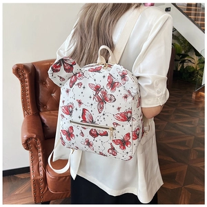 White PU leather backpack with red butterflies and star motifs worn by a model