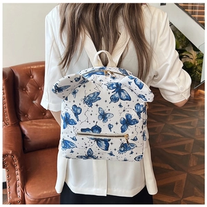 White canvas backpack with blue butterfly patterns and decorative animal ears on back