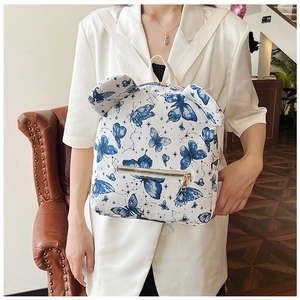 Detail of white mini backpack with blue butterfly prints and decorative animal ears