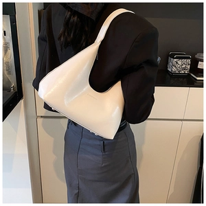 Close-up of a minimalist cream crescent shoulder bag with embossed branding on PU leather