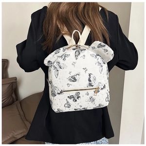 Close-up of white backpack with black butterfly prints and cute bear ear design detail
