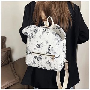 Detail of white backpack with black butterfly prints and cute ear design on a model