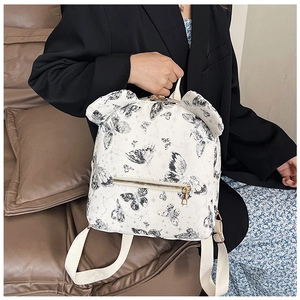 Detail of white butterfly print backpack with decorative ears and golden zipper