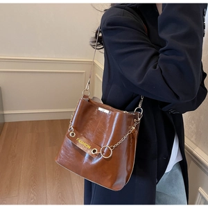 Detail of a brown leather bucket bag with gold chain strap and Fashion strap detail