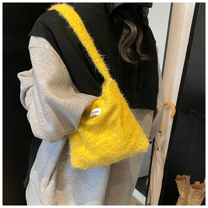 Dettaglio della borsa a tracolla in peluche giallo con etichetta FASHION e consistenza morbida