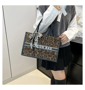 Détail du sac cabas léopard avec poignées noires et ruban à slogan tendance
