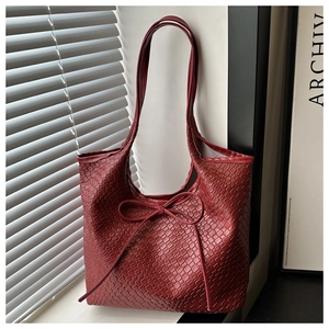 Close-up of deep red woven texture tote bag with minimalist bow detail on a sunny windowsill
