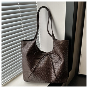 Close-up of dark brown woven tote bag featuring a decorative long ribbon bow knot