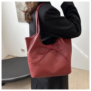Close-up of woven texture and bow detail on the dark red retro tote bag shown on shoulder