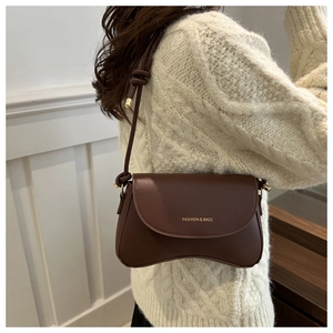 Detail of dark brown leather crossbody bag featuring unique curved bottom and flap design