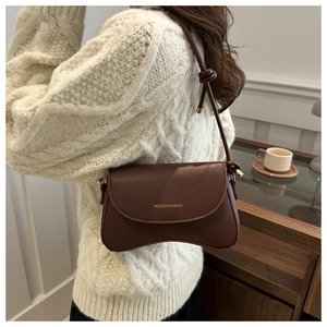 Detail of a dark brown leather underarm bag with knotted strap on a female model
