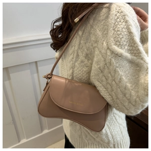 Close-up of curved light brown shoulder bag featuring gold fashion lettering and PU leather