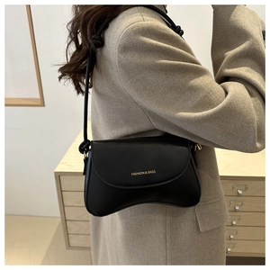 Detail of minimalist black faux leather flap bag with gold FASHION & BAGS lettering