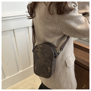 Detail of a brown crossbody bag with logo print and adjustable woven strap on a model