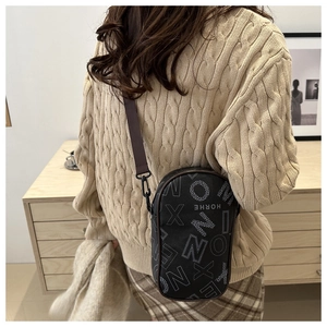 Detail of black crossbody bag with letter print and brown adjustable nylon shoulder strap
