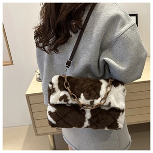 Detail of cow print plush shoulder bag with brown acrylic chain and soft faux fur texture
