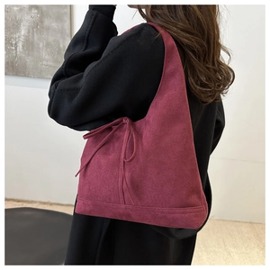 Detail of burgundy faux suede hobo bag featuring side tie knot bow and soft texture