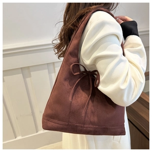 Detail of the brown suede tote bag featuring a decorative bow on the side for a sweet look