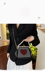 Detail of a black evening bag with red rhinestone heart and elegant pearl handle