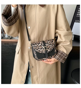 Detail of leopard print crossbody bag with gold buckle and black shoulder strap