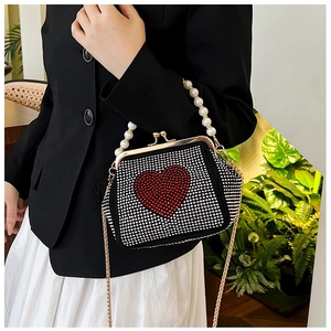 Close-up of heart-shaped rhinestone handbag with red crystal motif and pearl handle
