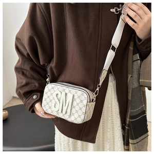Detail of elegant camera bag with wide strap and embossed texture on model