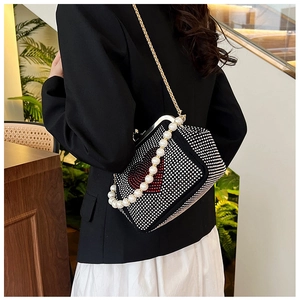 Detail view of heart-patterned rhinestone handbag with pearl handle and gold chain