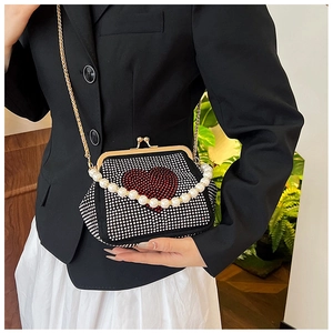 Detail of black rhinestone clutch bag with red heart crystal and pearl top handle