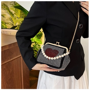 Detail view of black rhinestone evening bag with red heart and pearl handle on a model