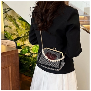 Detail of vintage rhinestone handbag featuring red heart and pearl beaded handle