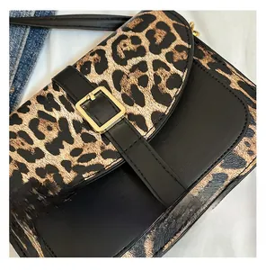 Detail showing leopard print texture and golden square buckle on the saddle bag