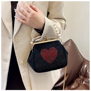 Detail of black crossbody bag featuring red rhinestone heart and elegant pearl handle