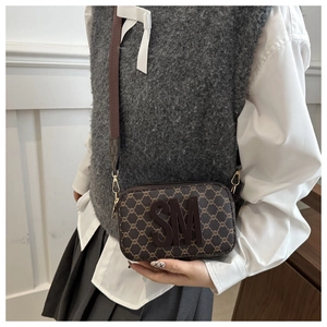 Close-up of brown monogram crossbody camera bag featuring a bold 3D SM logo and wide strap