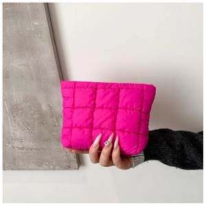 Detail of rose red quilted clutch bag with grid stitching pattern and soft texture