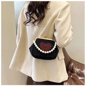 Macro detail of black evening bag with red rhinestone heart and pearl handle