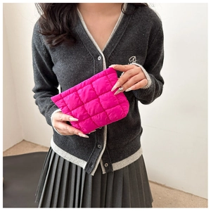 Close-up of vibrant rose pink quilted hand bag with a glossy nylon texture held by model