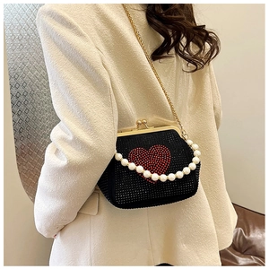 Detail of a black rhinestone crossbody bag with a red heart design and pearl handle