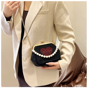 Detail of vintage heart rhinestone clutch with pearl handle and golden chain strap