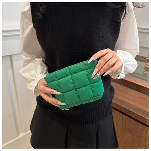 Macro view of green padded quilted pouch with soft stitching and smooth zipper detail