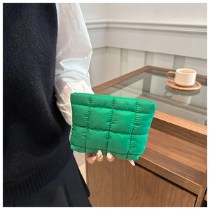Detail of green quilted puffer cosmetic bag showing texture and hand-held style