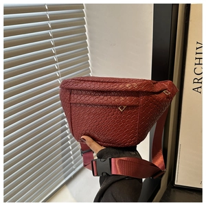 Detail of burgundy woven crossbody chest bag showing square grid texture and wide strap
