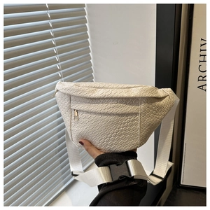 Close-up of cream woven waist bag with metal zipper and adjustable buckle strap