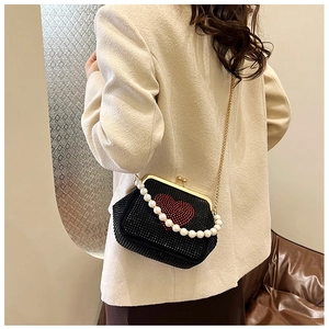 Detail of a luxury velvet bag featuring red rhinestone heart and pearl handle