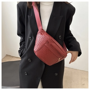 Close-up of red woven waist bag with golden zipper and adjustable shoulder strap