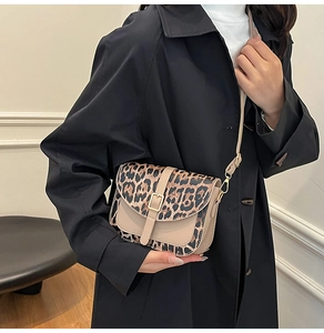 Detailed view of leopard print crossbody bag with golden buckle on black coat