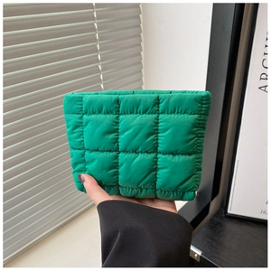Close-up of bright green quilted cosmetic bag with stitched checkered pattern held in hand