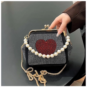Close-up of black evening bag with rhinestone heart, pearl handle, and gold chain