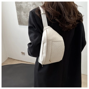 Detail of white crocodile pattern chest bag with adjustable strap and metal zipper